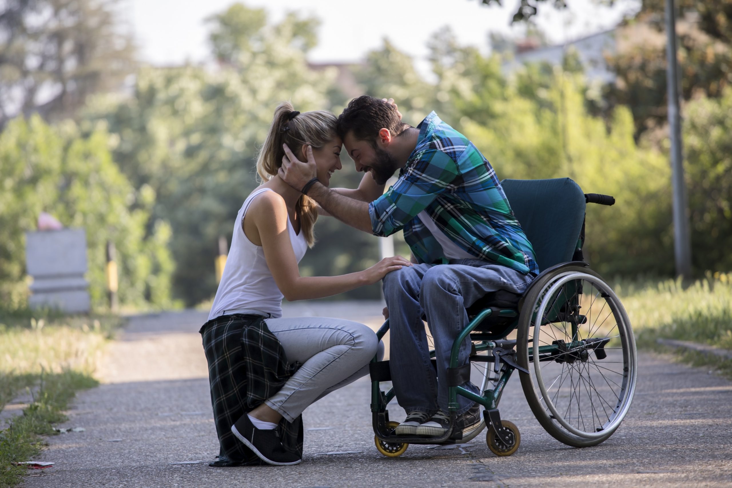 Couple walking in the park. The guy is a paraplegic in wheelchairs