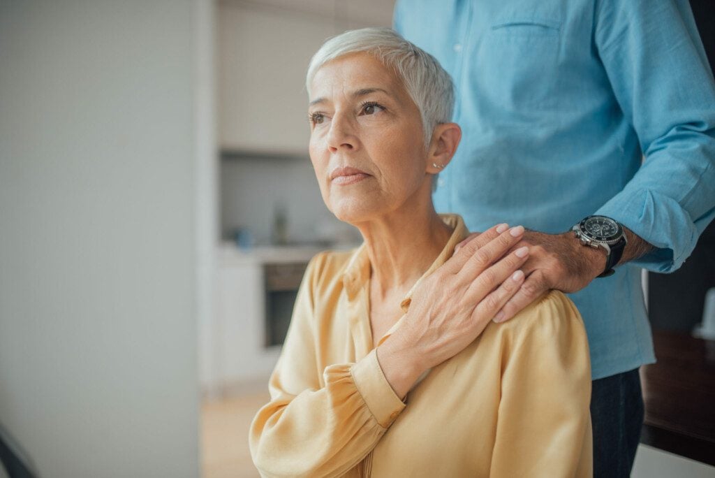 man with hand on woman's shoulder