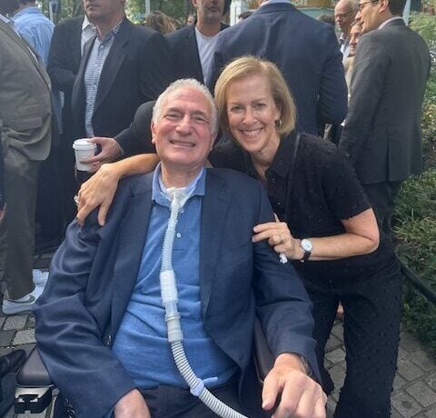 A woman hugging a man in a wheelchair.